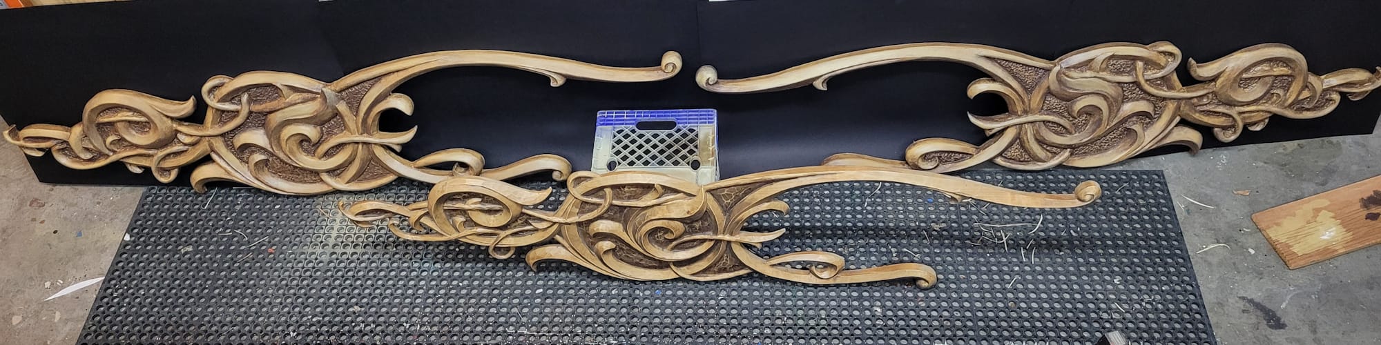 Three pieces of scrollwork positioned with little perceptible difference between the original left-hand scroll at the front and the two reproductions, left and right, behind.