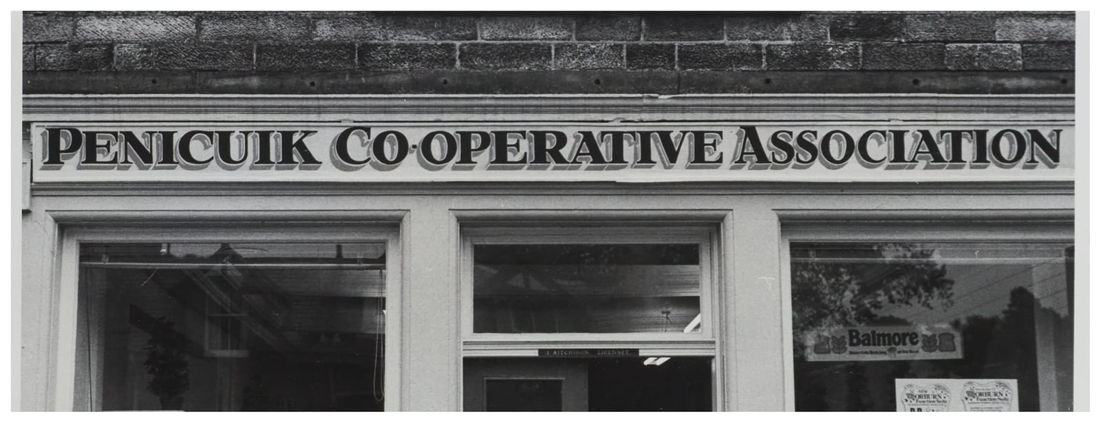 Fascia sign with dense hand-painted serifed lettering in black with a grey shade reading "Penicuik Co-Operative Association". 