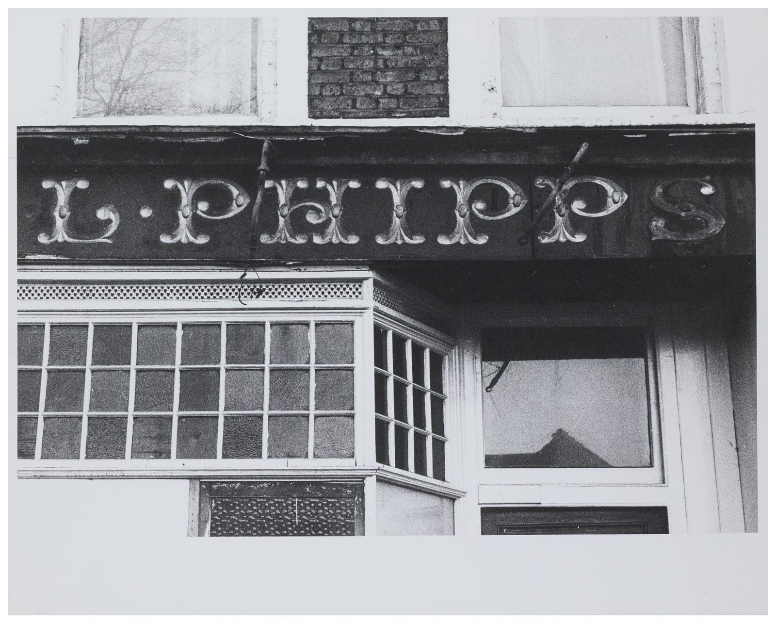 Fascia sign in ornamented Tuscan lettering that says "L. Phipps".