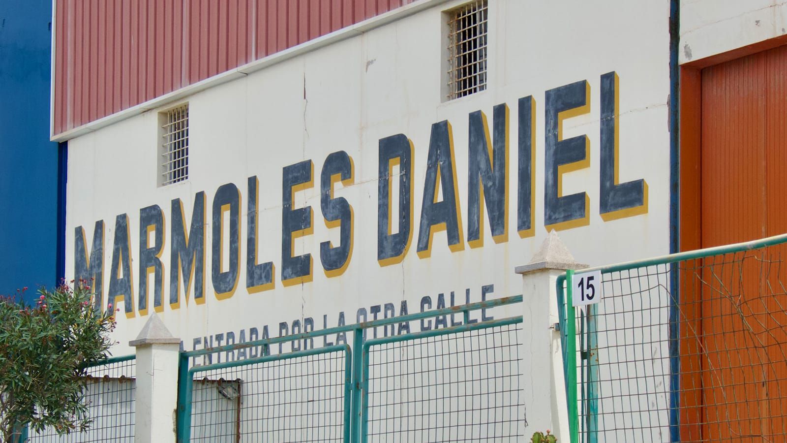Wall sign with tall sans serif letters painted dark blue with a yellow block shade.