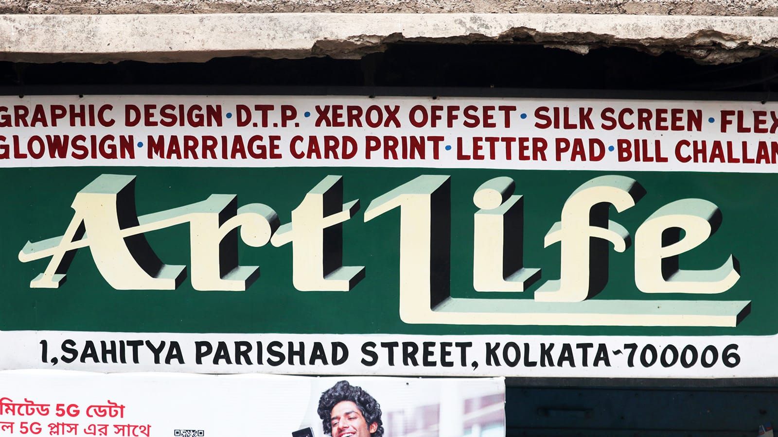 A painted sign for a DTP shop called “ArtLife”. The name is painted in white on a green background, and a list of their services is painted in red on white.