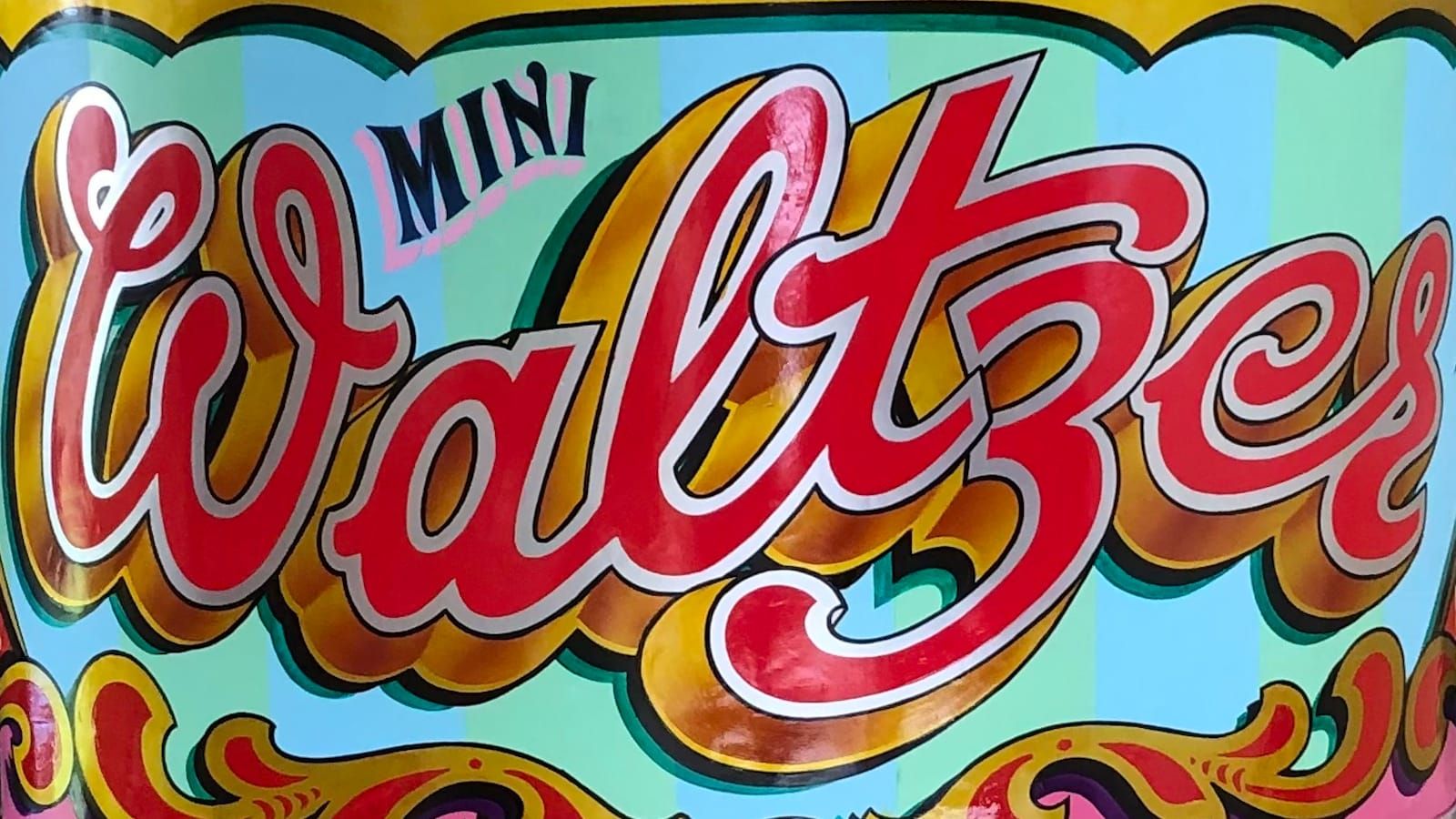 Curved side panel from a Waltzer fairground ride, lettered and flamboyantly decorated in bright colours and metal leaf.