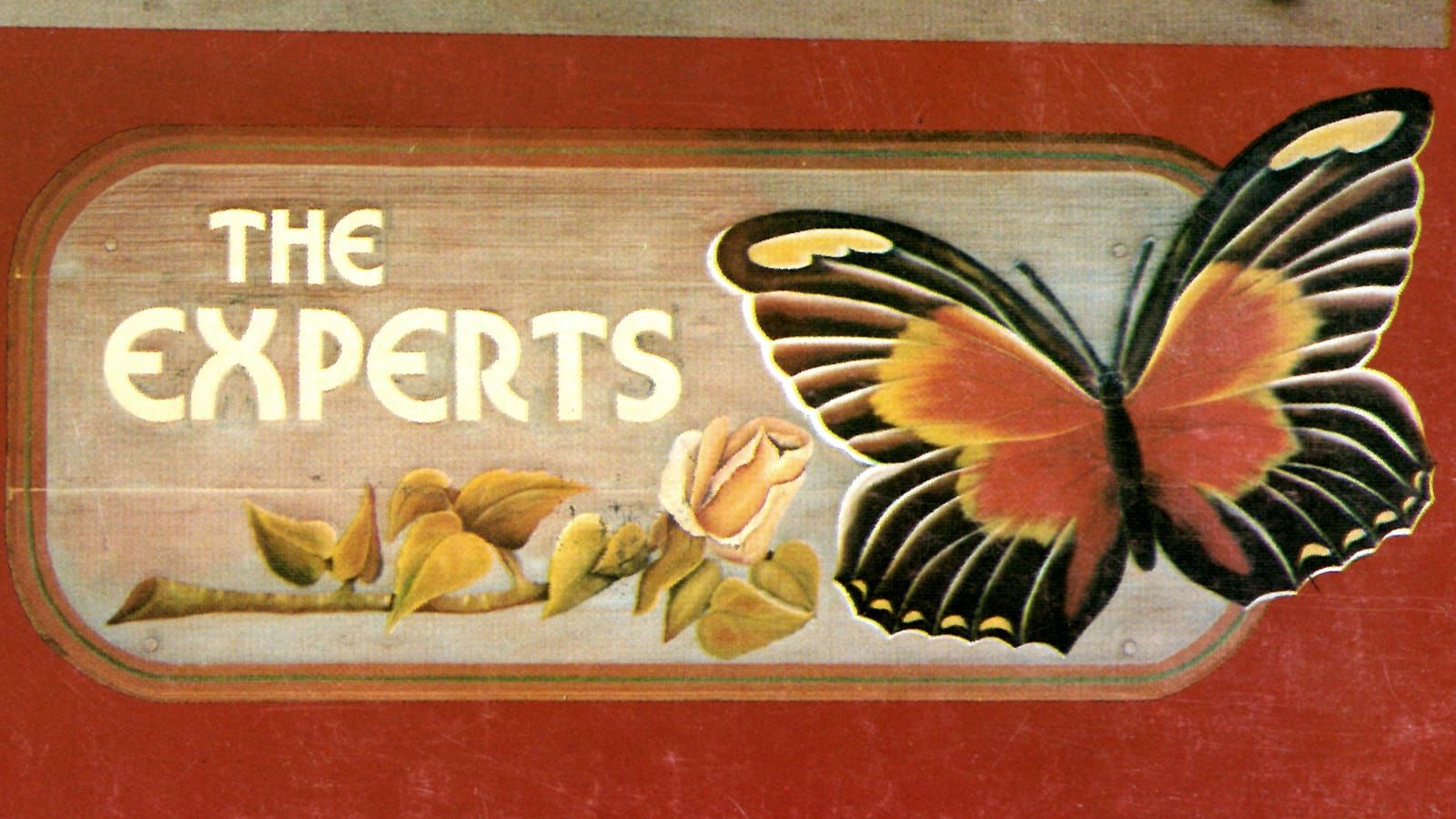Sign board with text saying "The Experts" underlined by a picture of a rose and with a large butterfly to the right.