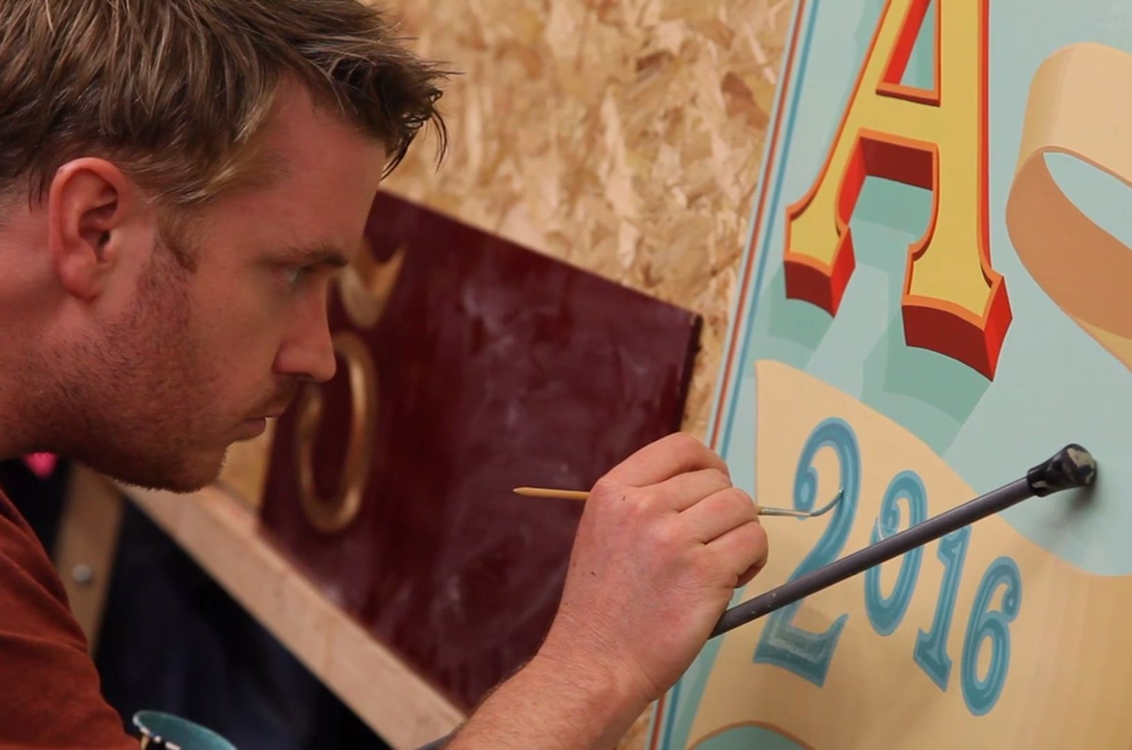Man painting a sign board with the date 2016.
