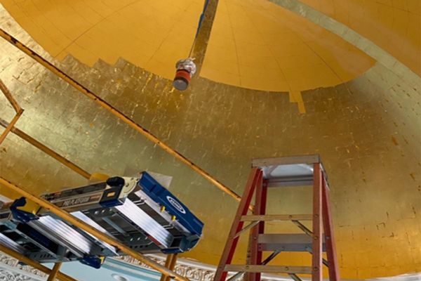 Ladders and a tower in place below a part-gilded dome.