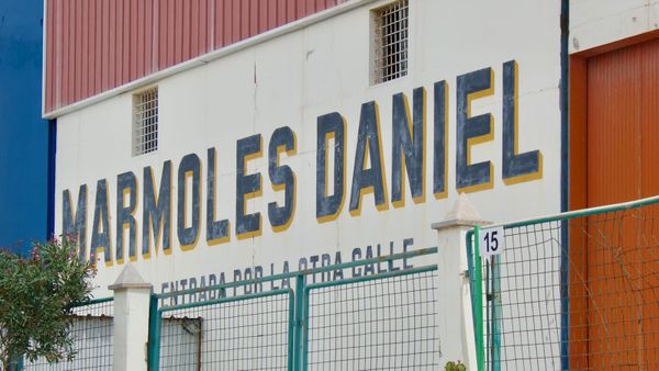 Wall sign with tall sans serif letters painted dark blue with a yellow block shade.