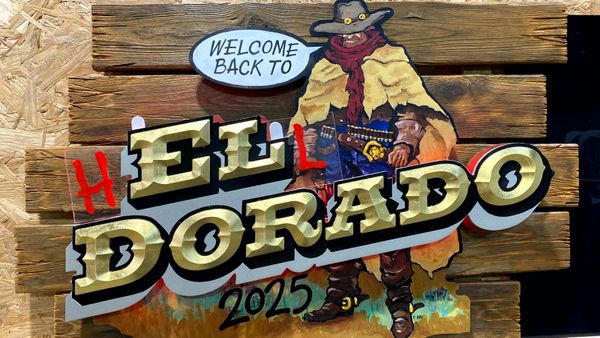 Painted and gilded panel with a cowboy pictured saying "Welcome Back To" above the main lettering that reads "El Dorado".