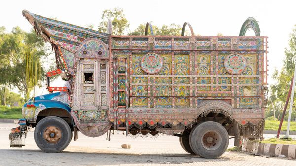 Profile photo of an ornate and colourfully decorated truck with its driver just visible in the cabin looking out.