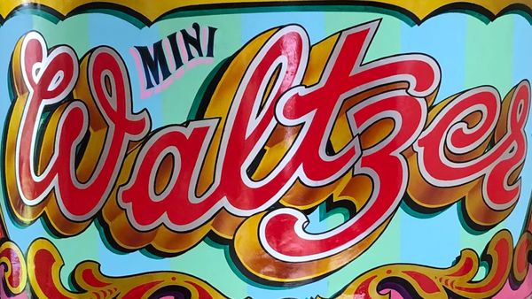 Curved side panel from a Waltzer fairground ride, lettered and flamboyantly decorated in bright colours and metal leaf.