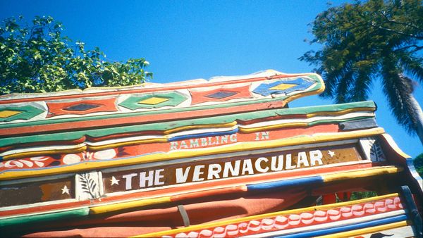 Portion of the side of a wooden vehicle with brightly coloured paint decorations. Lettering has been overlaid onto this reading "Rambling in the Vernacular".