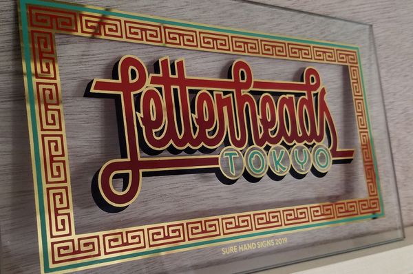 Gilded and painted glass panel that reads 'Letterheads Tokyo'.