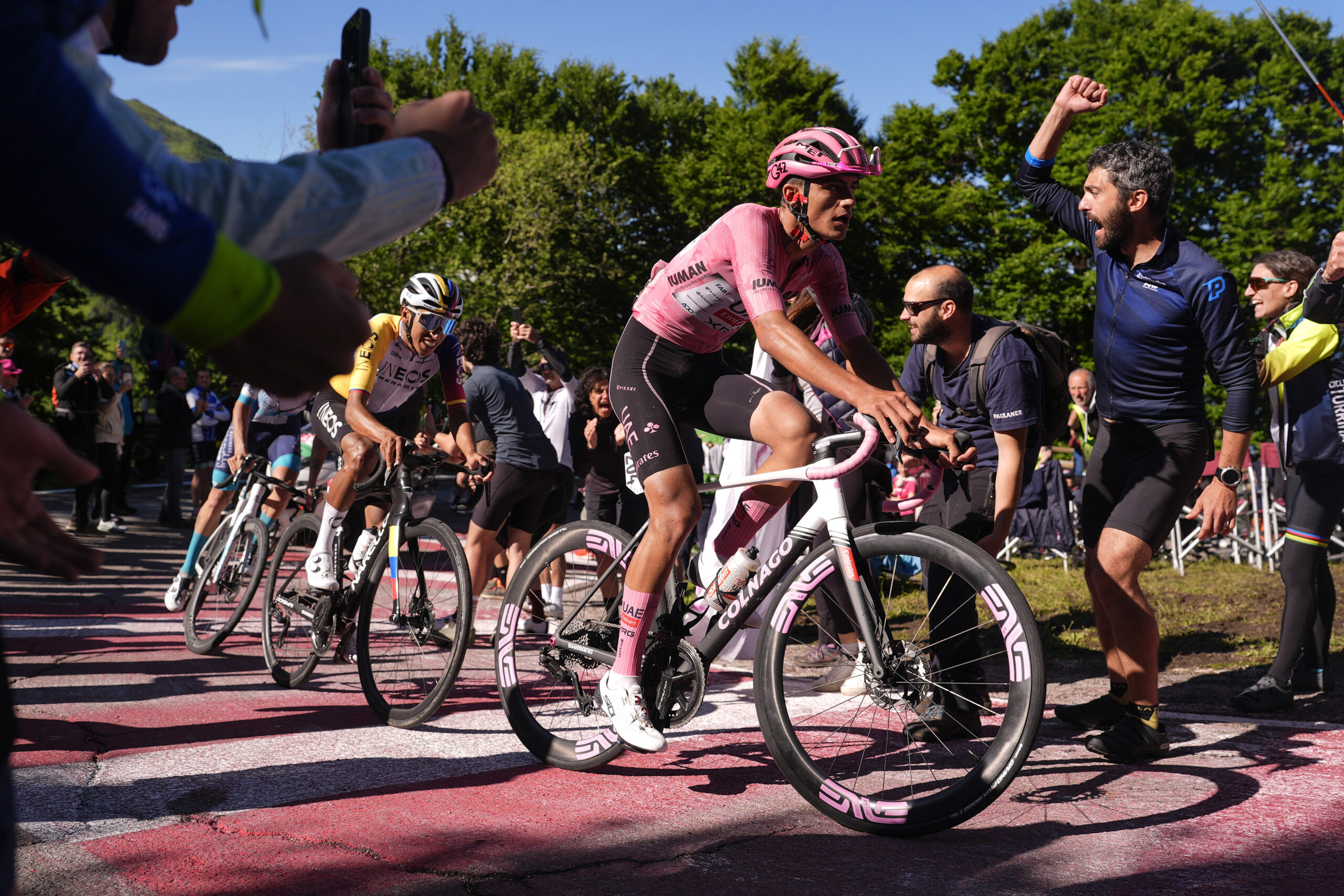 Isaac Del Toro, wearing the leaders' pink jersey, leads cyclists through a crowd at the Giro