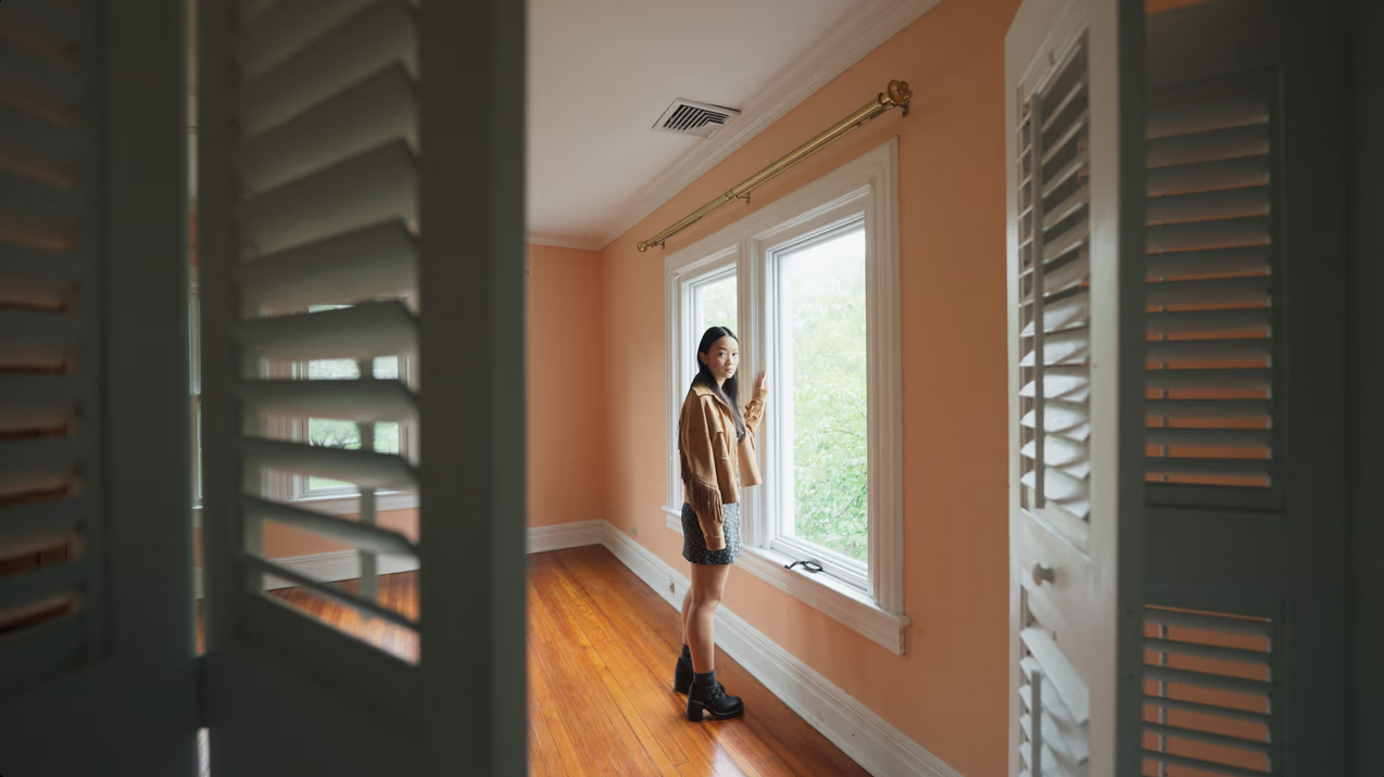 In Presnece, Callina Liang stands by a window and looks towards an open closet where the camera is looking from