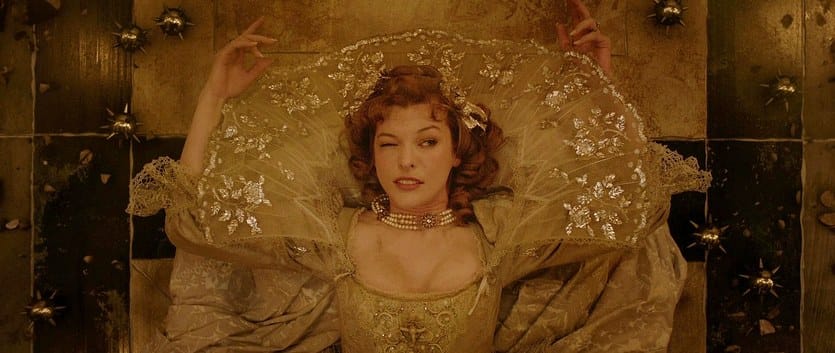 Milla Jovovich slides on the tiled floor through traps with one eye open in The Three Musketeers