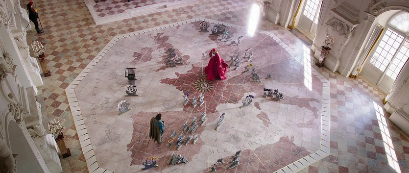 Christoph Waltz stands on a large battle map of Europe in The Three Musketeers