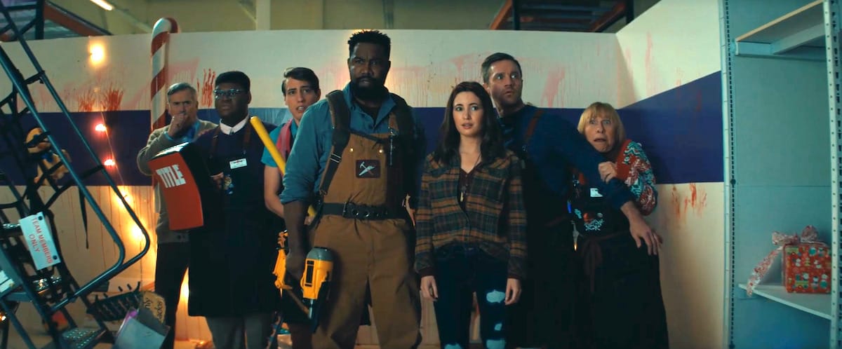 The staff in Black Friday, including Michael Jai White, Bruce Campbell, and Devon Sawa, huddle in fear while holding various implements from their store