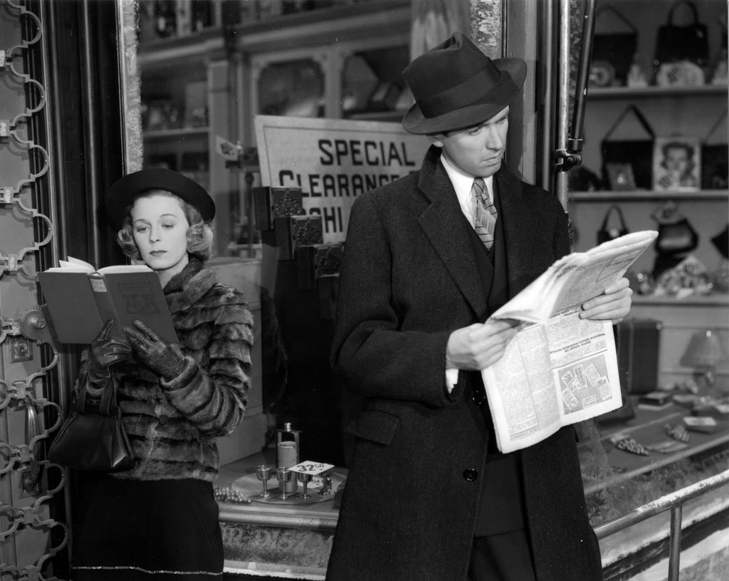 Outside a shop, Jimmy Stewart and Margaret Sullivan read separately, turned away from each other