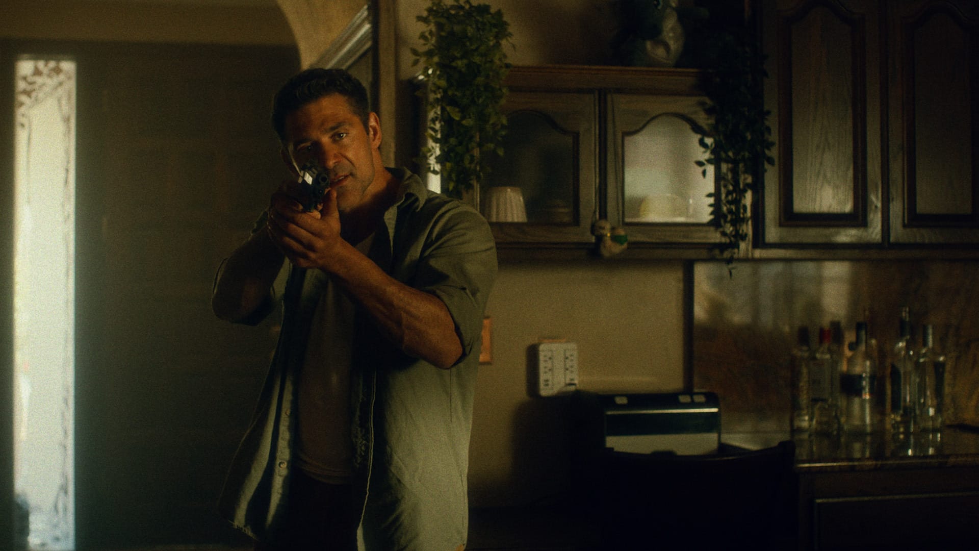Bren Foster holds a gun in a house in Mexicali