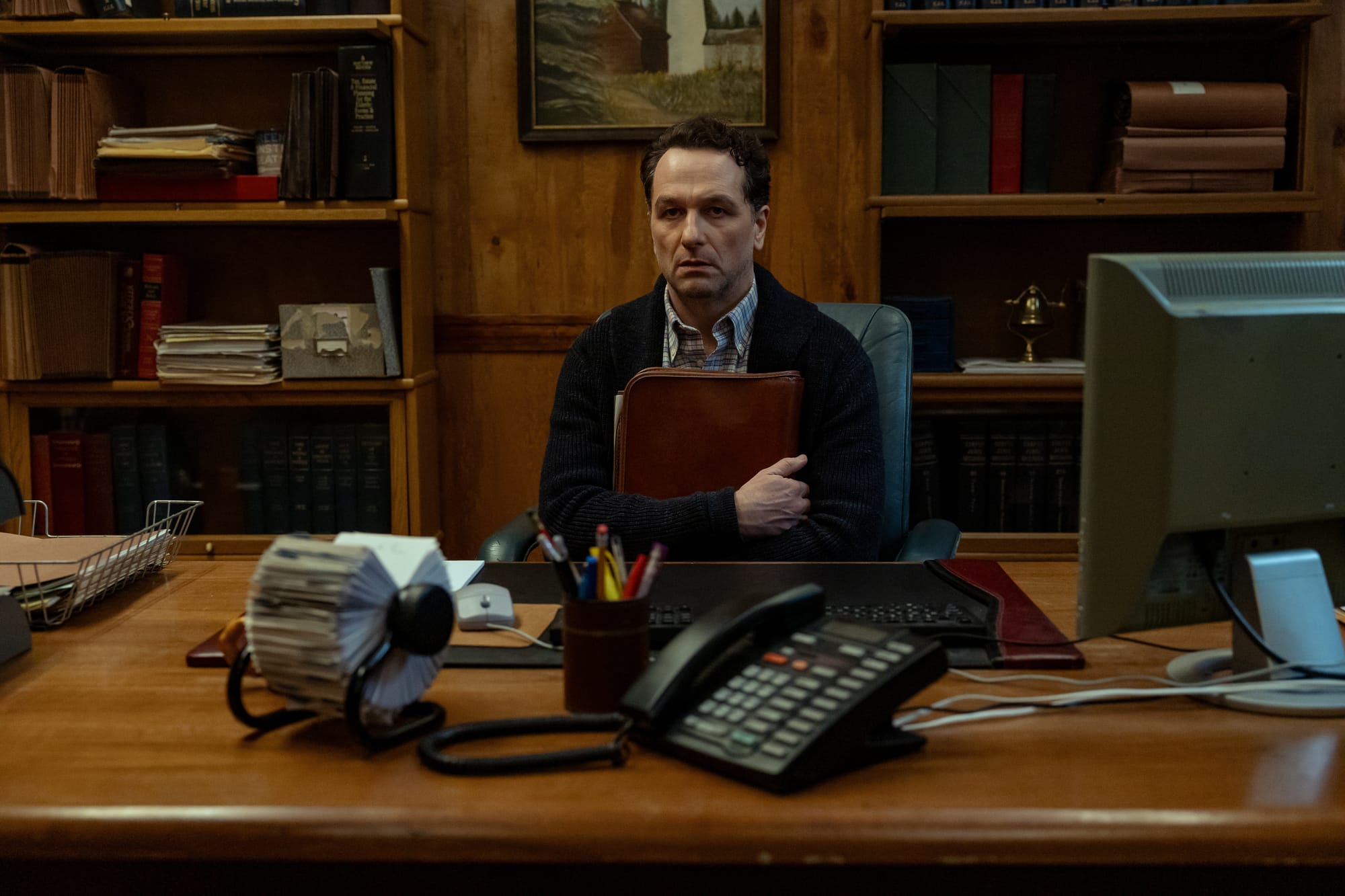 Matthew Rhys looks extremely stressed at his desk in Widow's Bay