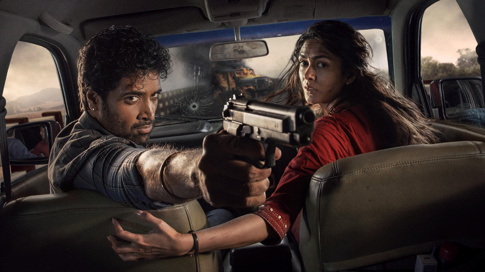 In promotional art for Dacoit: A Love Story, the two leads turn dramatically around in a car while the driver holds a gun