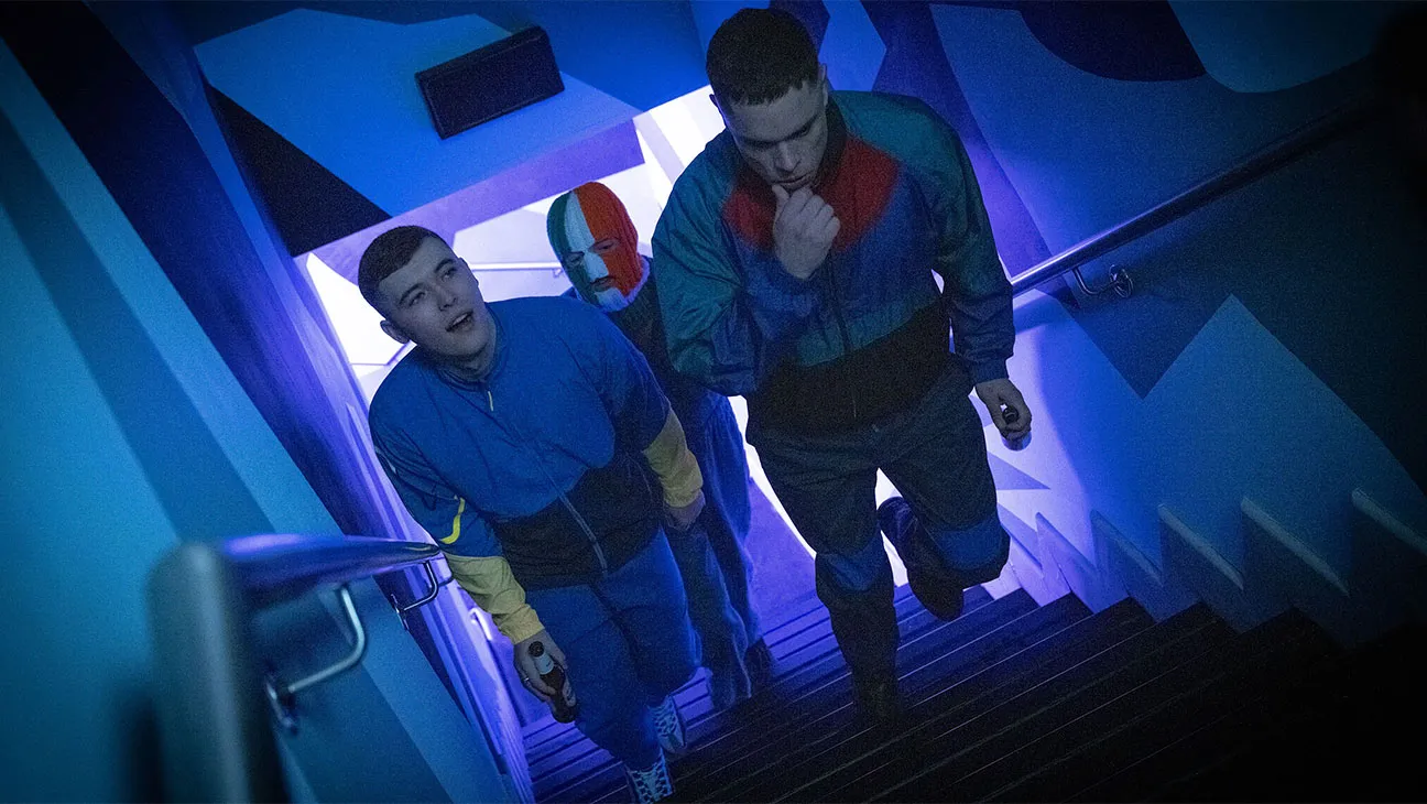 The members of Kneecap walk up a staircase at a concert venue
