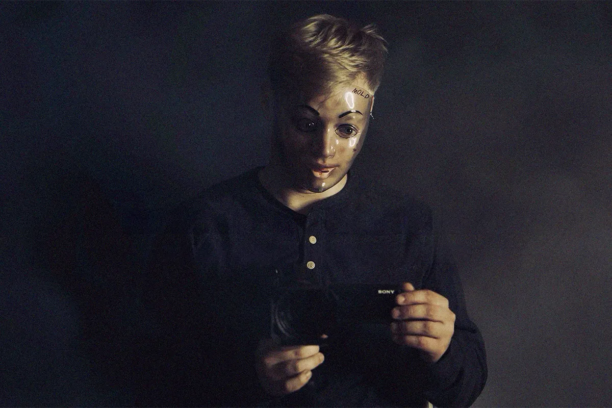 Curry Barker wearing a creepy mask and holding a camcorder in Milk & Serial