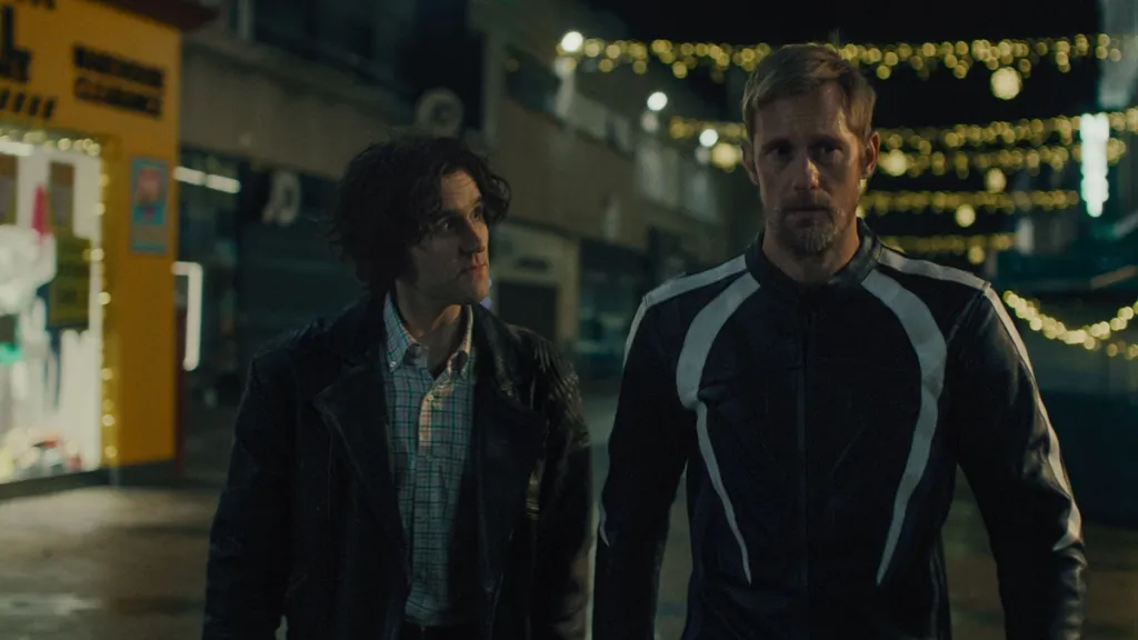 Harry Melling and Alexander Skarsgård walk next to each other in Pillion