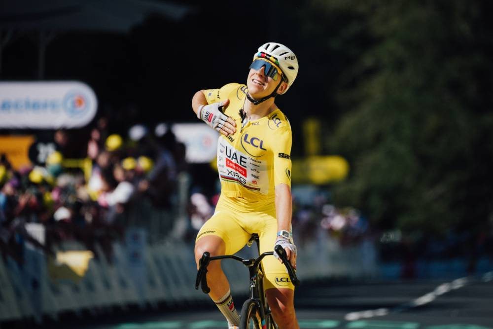 Tadej Pogacar taps his yellow jersey as he approaches the finish line in a Tour de France stage