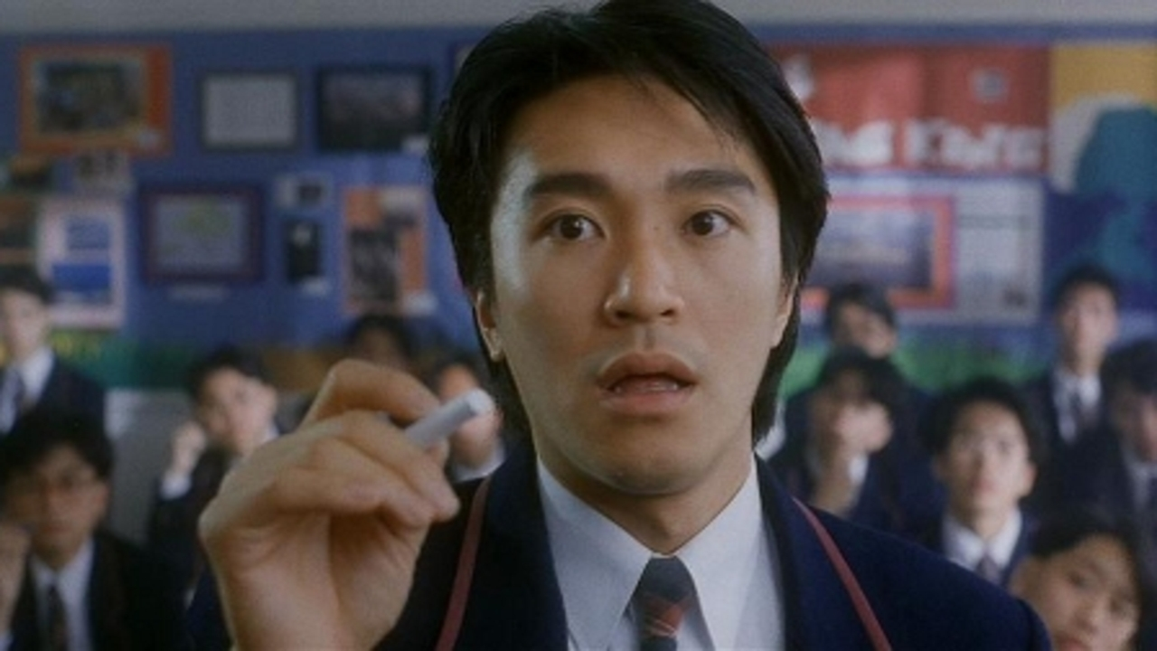 Stephen Chow holding a piece of chalk at the front of a classroom in Fight Back to School