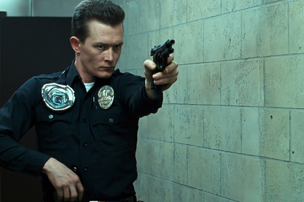Robert Patrick wearing an LAPD uniform and firing a gun in T2