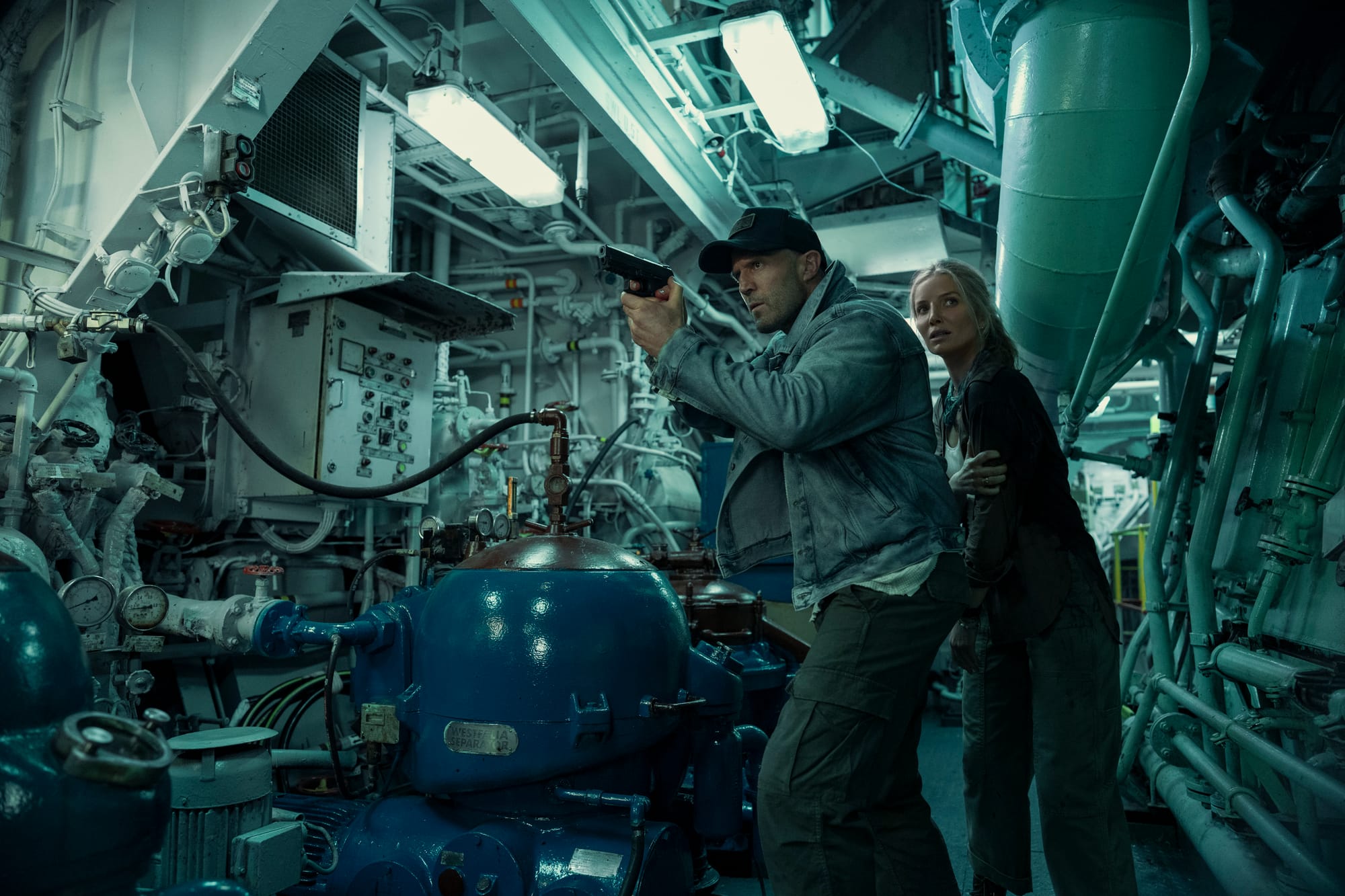 Jason Statham and Annabelle Wallis sneak through a room in a boat in Mutiny