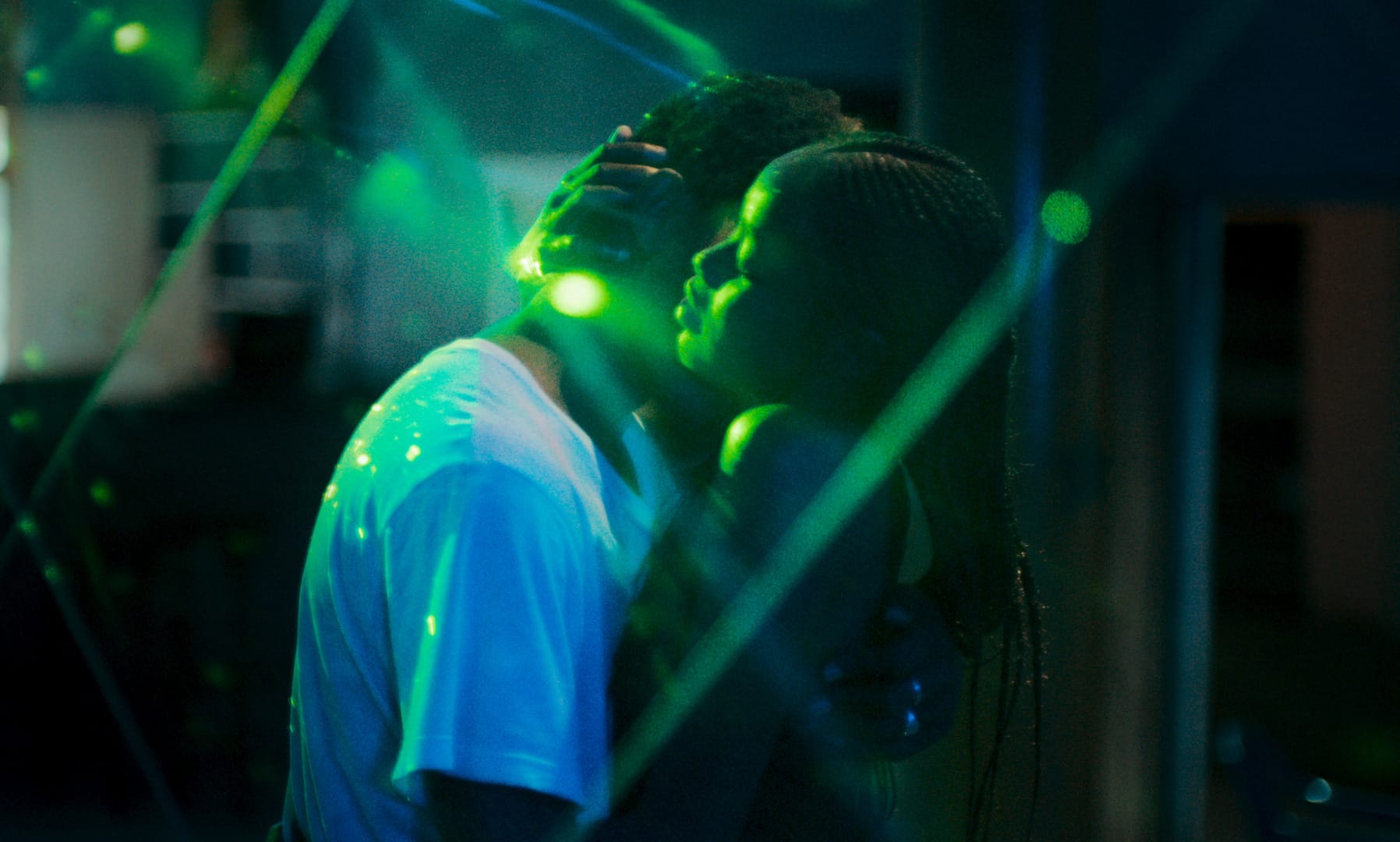 The leads in Atlantics embrace, green lights floating around them