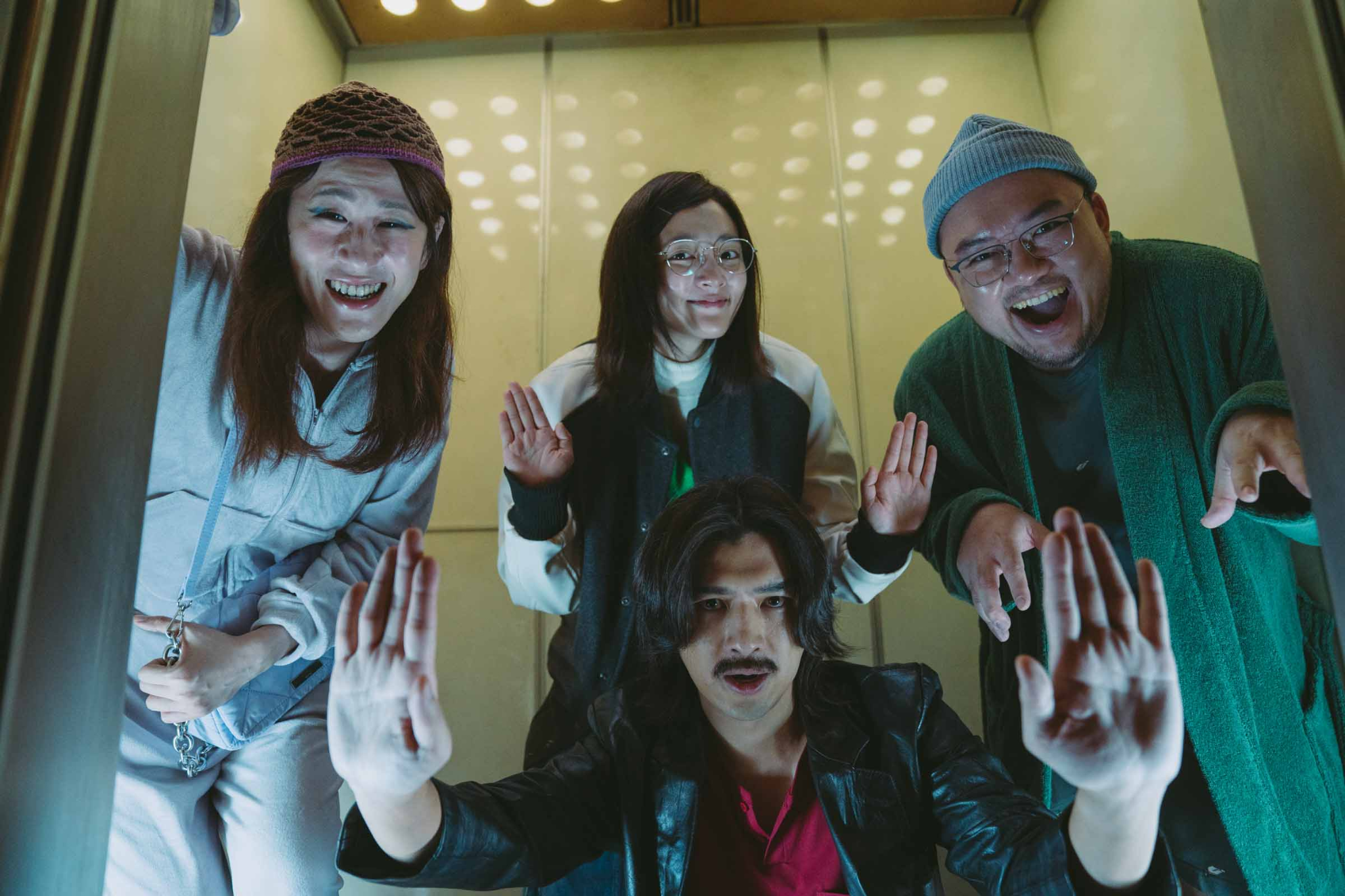 The leads of Dead Talents Society pose with their hands out in an elevator