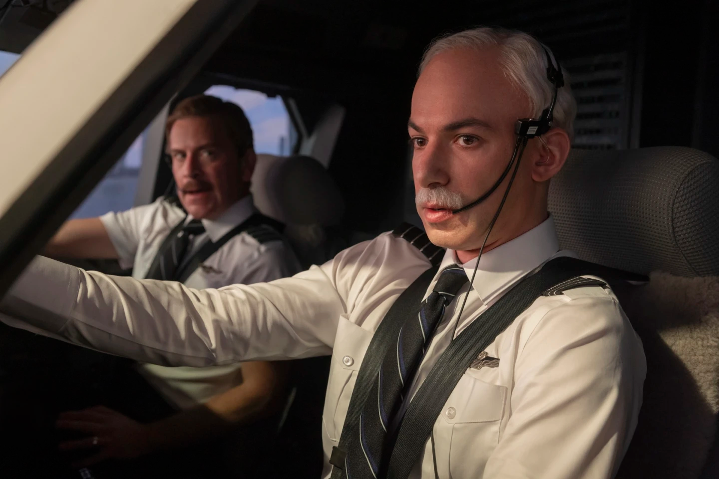 Nathan Fielder dressed and made up as Sully Sullenberger in a cockpit with another pilot in The Rehearsal