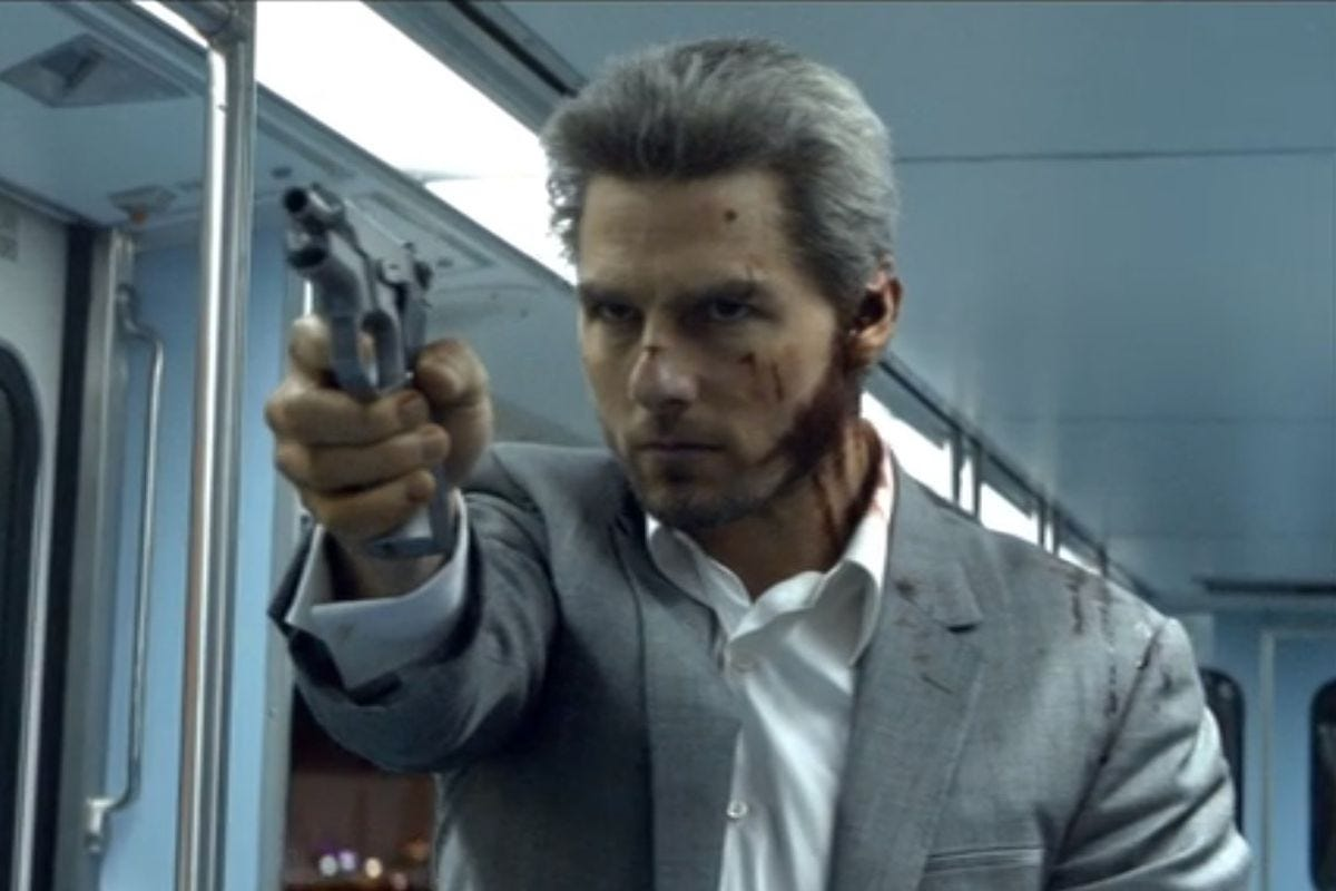A bloodied, gray Tom Cruise points a gun while on a subway train in Collateral