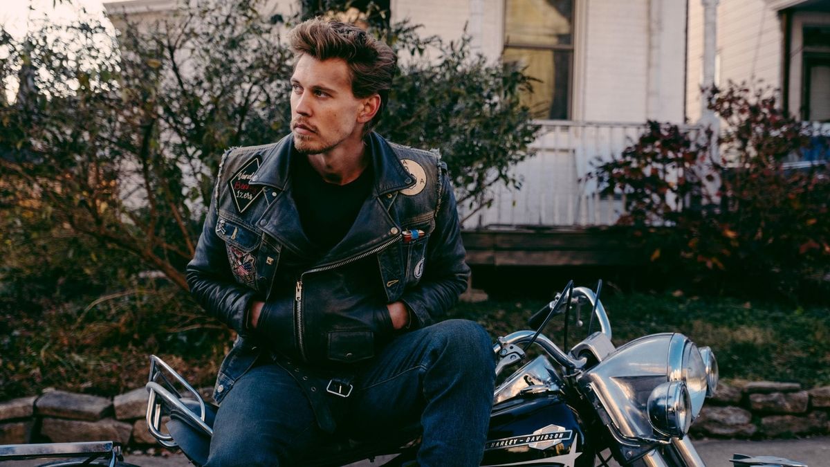Austin Butler, wearing a leather jacket, sitting on a motorcycle, and looking sexy in The Bikeriders