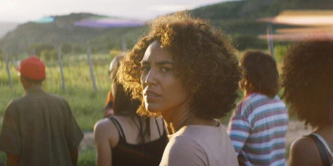A woman looks backwards towards the camera as other people walk forwards in Bacurau
