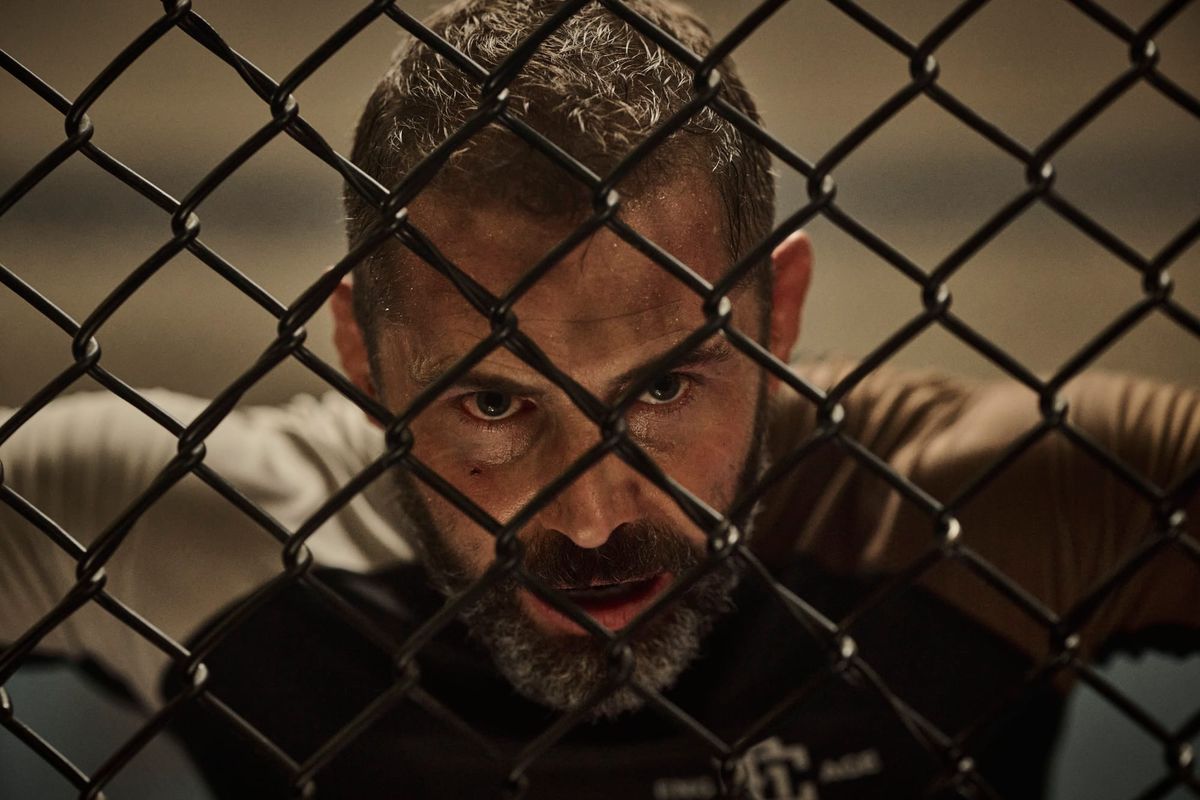 A tired, worn-down Daniel MacPherson is seen through the cage of an Octagon in Beast