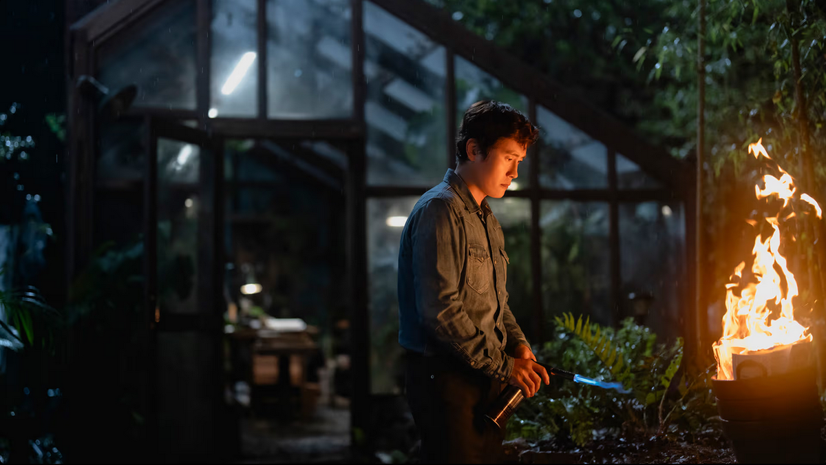 Lee Byung-hun burning some evidence in a greenhouse in No Other Choice