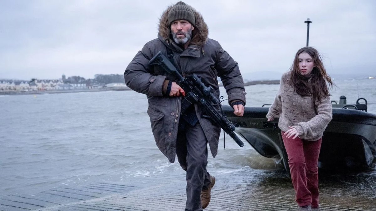 Jason Statham (with a scoped rifle) and Bodhi Rae Breathnach run on shore from a boat in Shelter