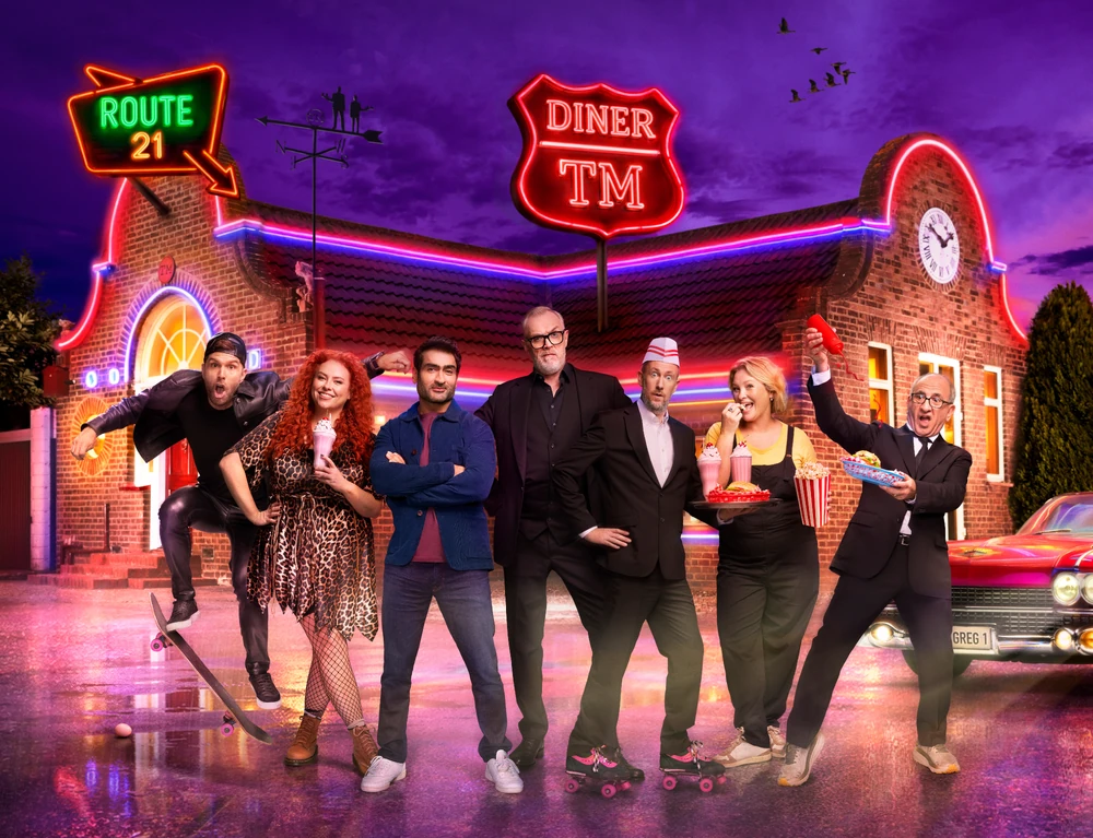 The cast for series 21 of Taskmaster posing outside of an American diner-style house