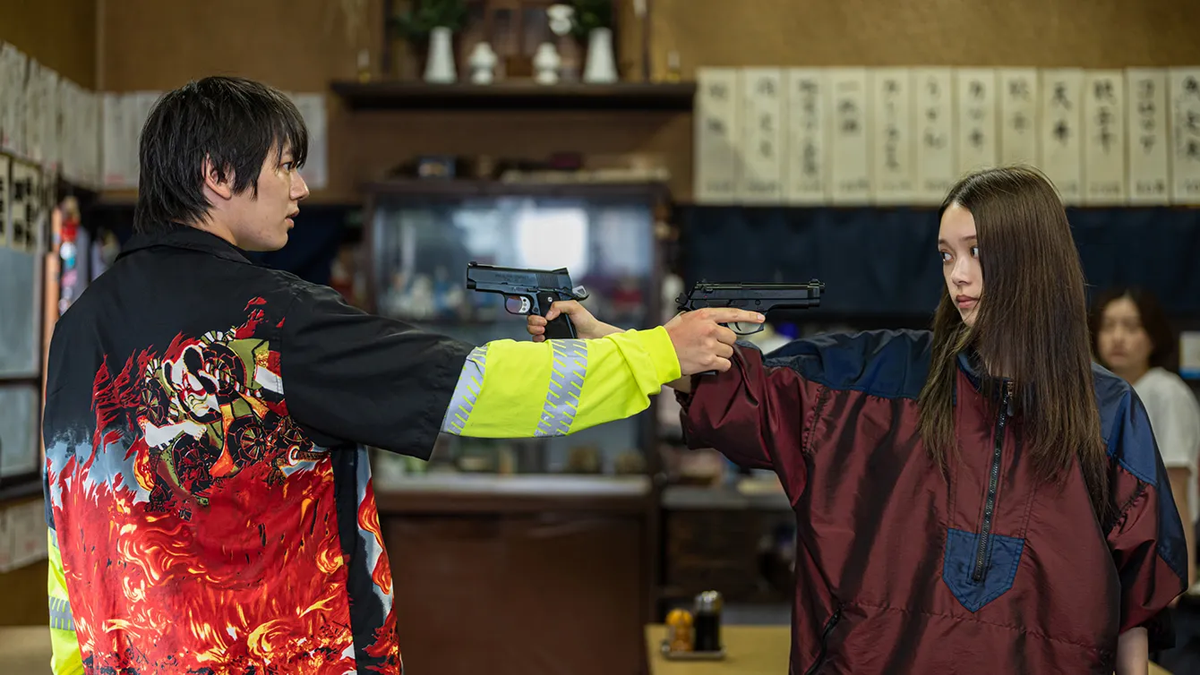 Tatsuomi Hamada and Akari Takaishi point pistols at each other in a restaurant in Baby Assassins 2