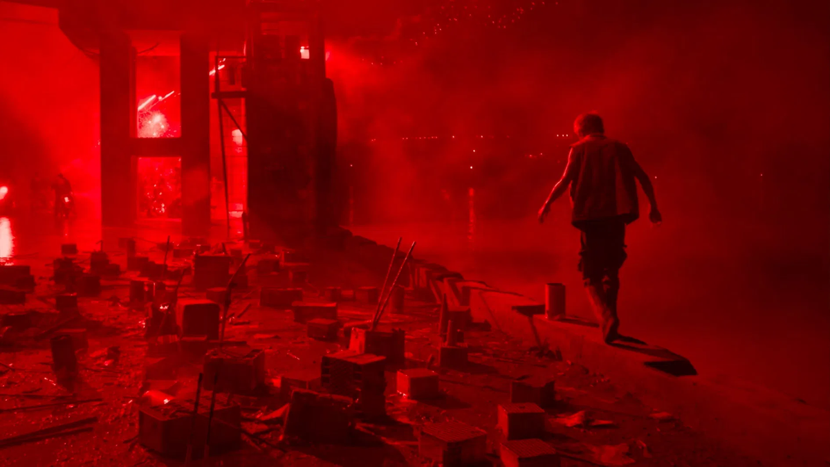 A red-tinted image of a man walking through a dusty area in Resurrection
