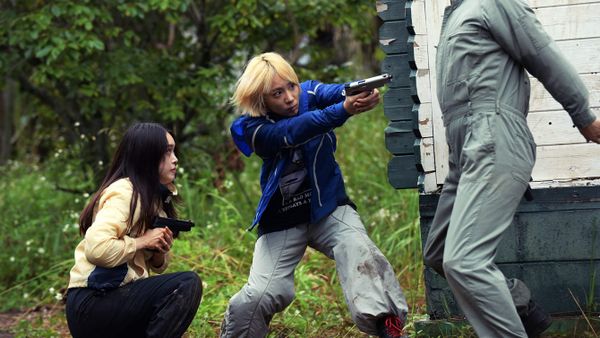 Mahiro and Chisato crouch and wield their guns in Baby Assassins 3