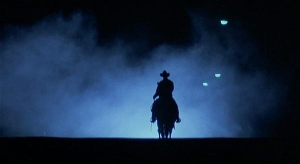 The silhouette of a horse rider trots through the fog in Near Dark
