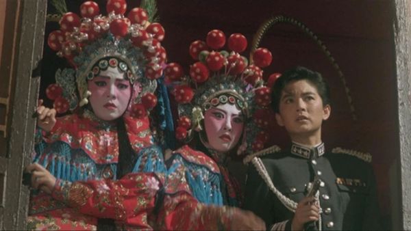In Peking Opera Blues, two people in extravagant Chinese opera costumes stand next to Brigitte Lin in a military uniform, all looking in surprise at something below them
