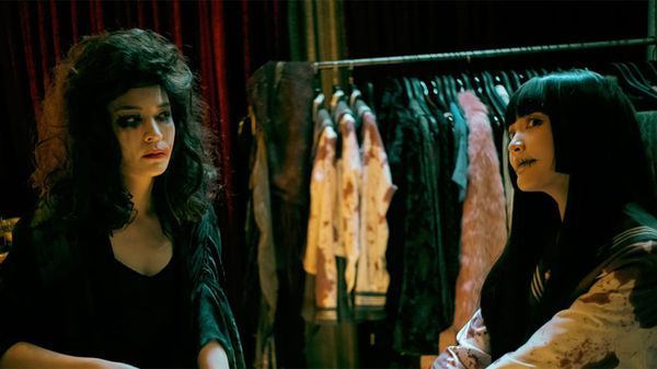 The two lead ghosts in Dead Talents Society in front of a ghost costume rack