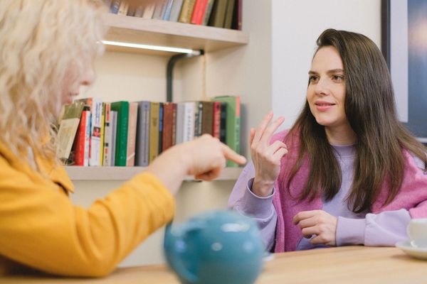 Two women engaged in a one-to-one conversation in a library