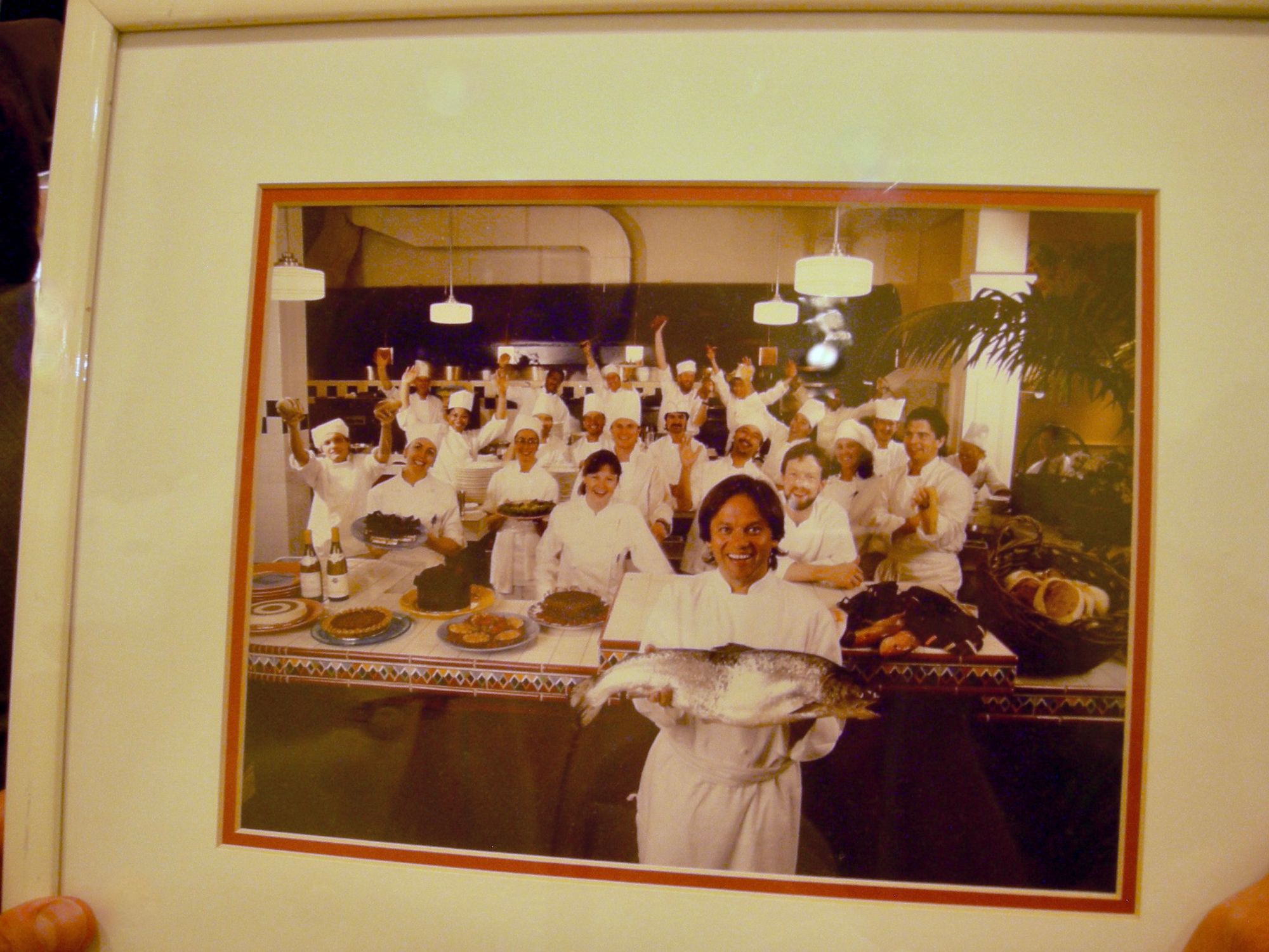 photo of wolfgang puck holding a fish with the kitchen team at postrio