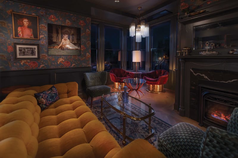 Left Door’s swanky living room style with a fireplace and tufted yellow couch